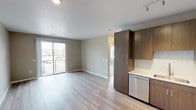 Located at 6137 Telluride Way in Denver, Colorado, this single-floor unit offers a thoughtfully designed layout with contemporary finishes throughout. The open-concept living and kitchen area is anchored by warm-toned luxury vinyl plank flooring that flows seamlessly through the main living space. The kitchen is well-appointed with rich, dark wood-grain cabinetry, light quartz countertops, a subway tile backsplash, a stainless steel undermount sink, and a full suite of stainless steel appliances including a refrigerator with ice maker, electric range, microwave, and dishwasher. Track lighting overhead adds a modern touch. A sliding glass door in the living area opens to a private balcony, flooding the space with natural light and offering neighborhood views. The bedroom features plush carpeting, a ceiling fan, multiple windows with horizontal blinds for ample natural light and privacy, and a built-in shelving unit ideal for storage or display. The bathroom is finished with large-format tile flooring, a full soaking tub with tiled surround, a white vanity with light countertop, and warm wood cabinetry above. Neutral wall tones throughout create a calm, cohesive aesthetic that complements the modern design of this well-laid-out Denver residence.