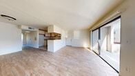 This single-story home offers a practical and well-organized layout accommodating four bedrooms and two bathrooms. The interior is unified by light wood-style flooring that extends throughout the main living areas and bedrooms, creating a clean, cohesive aesthetic. The open-concept living room is bright and airy, benefiting from natural light through a large window and sliding glass doors that provide direct outdoor access. The kitchen flows seamlessly from the living area and features white cabinetry with warm wood-tone trim, granite-style countertops, a breakfast bar peninsula, white appliances including a gas range, and a dishwasher, all set on classic white tile flooring. The four bedrooms are simply designed with neutral walls, wood-style flooring, and windows that bring in natural light. The primary bedroom includes a sliding-door closet with built-in shelving. The two bathrooms are functionally appointed — one features a full soaking tub with a shower curtain and granite-accented vanity, while the second offers a glass-enclosed walk-in shower alongside a wood-vanity with granite countertop. The overall ambiance is clean, neutral, and move-in ready, offering a straightforward and efficient use of space throughout.