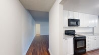 Located in Long Beach, California, this generously sized single-floor residence offers four bedrooms, two bathrooms, and a thoughtfully arranged layout connected by three hallways. Rich, dark hardwood-style flooring flows throughout the main living and kitchen areas, creating a warm and cohesive aesthetic.

The kitchen is well-appointed with crisp white cabinetry, granite-style countertops, a double sink, and black appliances including an electric range and built-in microwave. Ample upper and lower cabinet storage lines both sides of the galley-style kitchen, which opens conveniently toward the main living area.

The living room is bright and open, featuring a ceiling fan, a textured ceiling, and a sliding glass door that provides access to an outdoor area and brings in abundant natural light through vertical blinds.

The four bedrooms are carpeted for comfort and feature textured ceilings and large windows with vertical blinds that allow natural light to fill each room. The primary bedroom is generously sized, and select bedrooms include built-in closets with sliding doors and hanging rods for ample storage. Two additional closet spaces further enhance storage throughout the home.

The bathrooms are finished with hardwood-style flooring, extended granite-style vanity countertops with dual sinks, large mirrors, and windows for natural ventilation. The clean, neutral palette throughout the home provides a versatile canvas for any style.