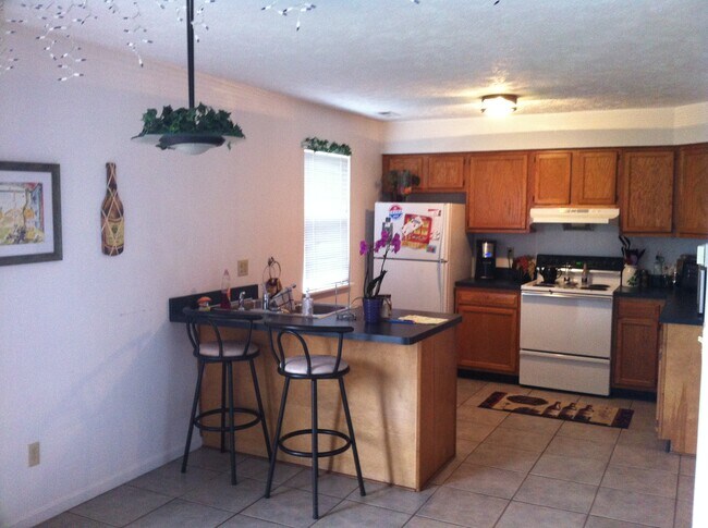 Kitchen with refrigerator/freezer, electric stove/oven, and dishwasher. (Microwave and stools in photo not provided) - 1409 Loop Road