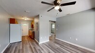 Located on Beach Blvd in Jacksonville, FL, this 2-bedroom, 1-bathroom single-story home offers a practical and well-appointed layout. Throughout the home, durable gray-toned vinyl plank flooring provides a cohesive, modern aesthetic, complemented by soft gray walls and crisp white trim.

The combined kitchen and living area forms the heart of the home. The kitchen features warm wood-toned cabinetry, ample counter space, a sink, and full-size appliances including a refrigerator and range. A back door with a decorative arched transom window offers an additional entry point and brings in natural light.

The living room is open and airy, with a ceiling fan, large windows overlooking the outdoors, and a textured ceiling. Both bedrooms are well-proportioned, each equipped with ceiling fans and multiple windows dressed with blinds that allow for generous natural light and views of the surrounding greenery. The rooms offer a calm, neutral atmosphere suitable for various furnishing arrangements.

The single bathroom is clean and functional, featuring gray-blue walls, wood-toned vanity cabinetry, a tiled shower-tub combination with a window above, and matching vinyl plank flooring. A hallway connects the main living spaces to the bedrooms and bathroom, keeping the layout efficient and easy to navigate.