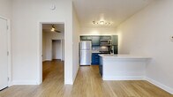 This thoughtfully laid-out one-bedroom, one-bathroom unit offers a clean, modern aesthetic throughout its single floor of living space. Light wood-tone flooring flows seamlessly through each room, complementing the crisp white walls and creating a bright, cohesive feel.

The open-concept living, dining, and kitchen area serves as the heart of the unit. The kitchen stands out with bold blue-green cabinetry, a decorative geometric tile backsplash, white quartz countertops, and a full suite of stainless steel appliances including a refrigerator, range, microwave, and dishwasher. A peninsula with a built-in sink provides additional prep space and a natural division between the kitchen and living area.

The living room is airy and inviting, featuring a ceiling fan with integrated lighting and a sliding glass door that opens to a private balcony with a railing — bringing in natural light and outdoor views.

The bedroom is a comfortable retreat, highlighted by a ceiling fan, a tall window with blinds for natural light and privacy, and two closets offering generous storage. The bathroom is well-appointed with blue-green vanity cabinetry, white quartz countertops, and a tub-shower combination with elegant marble-style tile surround.