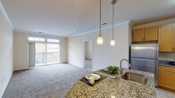 This single-floor residence offers a well-organized, open layout that connects the kitchen and living area seamlessly. The kitchen is appointed with warm honey-toned cabinetry, granite countertops, and a full suite of stainless steel appliances, including a range with over-the-range microwave and a full-size refrigerator. A peninsula with pendant lighting provides additional counter space and serves as a casual dining or prep area.

The living area is generously sized, featuring neutral-toned carpet, crown molding, and a sliding glass door that opens to a private balcony, allowing natural light to fill the room. The layout connects comfortably to additional rooms via interior doorways.

The bedrooms are carpeted and finished with neutral walls, offering a calm atmosphere. One bedroom includes a walk-in closet and is served by a full bathroom featuring warm tile surround, a combined tub and shower, and a vanity with wood cabinetry and a white countertop. A second bathroom includes a glass-enclosed walk-in shower with coordinating tile and a similarly styled vanity. Throughout, the design maintains a consistent, clean aesthetic with practical finishes suited for everyday living.