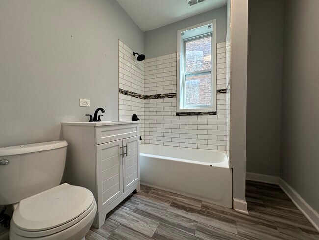 Fully renovated bathroom with subway tile tub surround and new vanity and toilet - 5653 S May St