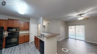 Located at 179 Peatmoss Dr in Fayetteville, NC, this single-story, 2-bedroom, 2-bathroom residence offers a well-organized and functional floor plan. The open-concept living and dining area flows seamlessly from the kitchen, which features warm medium-toned wood cabinetry, granite-style countertops, a peninsula with breakfast bar seating, and black appliances including a refrigerator, range, microwave, and dishwasher. Light gray luxury vinyl plank flooring runs throughout the entire home, creating a cohesive and easy-to-maintain aesthetic. A sliding glass door in the living area provides access to the outdoors and allows natural light to fill the space. The primary bedroom is a comfortable size and includes a ceiling fan, a window with outdoor views, and closet access. The second bedroom also features a ceiling fan, natural light from a window, and its own closet. Both bathrooms are appointed with warm wood vanities, light countertops, and framed mirrors with overhead lighting. A dedicated hallway connects the bedrooms and bathrooms, enhancing privacy. The neutral warm-beige color palette throughout gives the home a clean, move-in-ready feel.