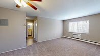 Located at 680 Smith Ct in Rocky River, OH, this one-bedroom, one-bathroom unit offers a practical and comfortable layout across a single floor. The living room is the heart of the space, featuring neutral-toned carpet, a ceiling fan with light fixture, baseboard heating, and a wall-mounted air conditioning unit. A window allows natural light to brighten the room, while a hallway leads toward the kitchen and bathroom. The kitchen is visible from the living area and includes overhead vanity lighting, providing a functional cooking space. The bedroom is a well-proportioned retreat with its own window overlooking the surrounding trees, baseboard heating, and soft carpeting underfoot. Three closets throughout the unit offer generous storage options. The full bathroom features a soaking tub with floor-to-ceiling tiled surround in rich, dark earth tones, adding a distinctive design element. Neutral gray walls and consistent carpet flooring throughout create a cohesive, understated aesthetic. The textured ceilings and clean white trim complement the overall simple, functional character of this Rocky River residence.