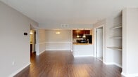 This single-floor residence is designed with an open, functional layout that connects the living area directly to the kitchen. The living and dining space features rich, dark hardwood-style flooring, neutral-toned walls with a chair rail detail, and a textured ceiling. Built-in shelving is incorporated along one wall, adding practical storage and display space. The kitchen is anchored by a peninsula with granite-style countertops, rich dark wood cabinetry, black appliances including a refrigerator, electric range, and microwave, and a mosaic tile backsplash. Pendant lighting above the peninsula provides focused illumination, complemented by an additional wall-mounted fixture in the living area. A dedicated pantry with wire shelving is accessible directly from the kitchen.

The bedrooms are carpeted with neutral tones and feature textured ceilings, with windows that allow natural light to filter in. One bedroom includes access to a walk-in closet. Two full bathrooms are present, each with a tub-shower combination featuring white tile surrounds. One bathroom includes hardwood-style flooring and a dark wood vanity with a granite-style countertop, while the other offers a clean, minimal design. The overall ambiance is straightforward and well-maintained.