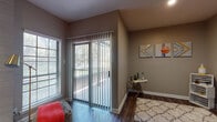 This single-floor residence offers a thoughtfully designed layout with a cohesive neutral color palette and rich dark hardwood-style flooring carried throughout. The open living area serves as the heart of the home, anchored by a sleek fireplace set against a textured accent wall, creating a warm and inviting focal point. A ceiling fan adds both style and function to this space, which also benefits from a sliding glass door that floods the room with natural light and provides access to an outdoor area with lush greenery views. Additional windows fitted with horizontal blinds further enhance the brightness of the living space. The galley-style kitchen is well-equipped with white cabinetry, marble-style countertops, a dark tile backsplash, and black appliances including a range, over-the-range microwave, and refrigerator. The bedroom is generously sized and features a walk-in closet with built-in shelving and hanging rods, offering excellent storage. A second door from the bedroom provides additional access. The bathroom includes a tub-shower combination with modern tile surround, hardwood-style flooring, and classic brushed nickel fixtures. Throughout the residence, clean white baseboards and trim provide a crisp contrast to the warm wall tones, lending a polished, move-in-ready feel.