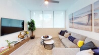 Located at 215 SE 5th St in Hallandale Beach, Florida, this contemporary 2-bedroom, 2-bathroom residence offers a clean, modern aesthetic throughout its thoughtfully designed single-floor layout. Light wood flooring flows through the main living areas, complementing a bright and airy atmosphere enhanced by large windows fitted with roller shades and ceiling fans.

The open kitchen is a standout feature, showcasing flat-front white cabinetry extending to the ceiling, a striking marble-style backsplash, quartz countertops, and a full suite of stainless steel appliances including a range, built-in microwave, dishwasher, and refrigerator. A rustic wood dining table with wire chairs adds a stylish contrast to the kitchen's crisp palette.

The living area is comfortable and well-proportioned, with natural light filtering through wide windows. Both bedrooms are generously sized, each offering large windows, ceiling fans, and ample natural light. The primary bedroom features a spacious walk-in closet with built-in shelving organization. A convenient in-unit stacked washer and dryer is tucked just off the bedroom hallway.

Both bathrooms are finished with floor-to-ceiling marble-style tile, glass-enclosed tub/shower combinations, and modern vanities, lending a polished, spa-like quality to the space.