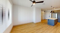 Located at 1745 W Desert Hollow Dr in Phoenix, AZ, this well-appointed 2-bedroom, 2-bathroom unit offers a thoughtfully designed single-floor layout. The open-concept kitchen and living area serves as the heart of the home, featuring a large central island with a crisp white quartz countertop, dual pendant lights, and a full suite of stainless steel appliances. Two-tone cabinetry — warm wood uppers paired with slate gray lowers — adds a contemporary aesthetic, complemented by a white tile backsplash and recessed lighting. Light wood flooring flows throughout the main living areas, enhancing the bright and airy atmosphere. The living room is fitted with a ceiling fan and a glass door that opens to a balcony with open desert views. The spacious primary bedroom also features a ceiling fan, while both bedrooms include soft carpet flooring and generous natural light. A walk-in closet with built-in shelving and hanging rods provides ample storage. The primary bathroom includes a glass-enclosed shower, a gray vanity with white countertop, and a sleek black-framed mirror. The second bathroom offers a full soaking tub and shower combination with matte black fixtures and wood-look tile flooring.