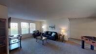 Located at 4300 Collegiate Way in Mount Pleasant, Michigan, this single-floor residence offers a comfortable and functional layout designed for everyday living. The generously sized living room features plush carpeting, neutral-toned walls, and large windows that invite abundant natural light while offering views of the surrounding exterior. The open feel of the space is complemented by its seamless flow into a dedicated dining area, which comfortably accommodates a round table and chairs. The kitchen is fully equipped with ample light wood cabinetry, generous countertop space, a full suite of appliances including a range, refrigerator, and dishwasher, and a classic checkered tile floor that adds character to the room. The residence includes multiple carpeted bedrooms, each featuring windows with blinds that allow for natural light and privacy. The rooms offer a calm, neutral palette ideal for rest and study. Two full bathrooms are present, each outfitted with a tub-shower combination, vanity with under-sink storage, a mirror, and tile flooring. Overall, the space presents a clean, practical, and well-organized interior suited for comfortable residential living.