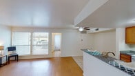 This single-story residence in Lufkin, Texas, offers a well-organized layout across two bedrooms and two bathrooms. The open-concept living and dining area serves as the central hub of the home, featuring warm wood-look laminate flooring, a ceiling fan with light fixture, and large windows that allow generous natural light to fill the space. A half-wall peninsula separates the living area from the kitchen, providing a convenient breakfast bar with granite-style countertops.

The galley-style kitchen is equipped with warm wood cabinetry, a double-basin sink, granite-style countertops, a white electric range, and a full-size refrigerator. Light tile flooring runs throughout the kitchen and entry areas, offering a clean, durable surface.

Both bedrooms feature plush carpeting and windows overlooking the outdoors, creating a calm and comfortable atmosphere. One bedroom includes access to a walk-in closet, adding practical storage. The bathrooms feature granite-style vanity countertops with wood cabinetry. Throughout the unit, a neutral white and cream color palette creates a bright, cohesive aesthetic.
