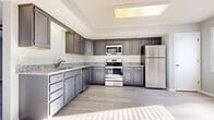 Located at 99 Glenview in Ontario, Ohio, this two-floor home offers a clean, modern aesthetic throughout its well-appointed layout. The kitchen serves as a standout feature, showcasing gray shaker-style cabinetry, granite-look countertops, and a full suite of stainless steel appliances including a refrigerator, electric range, microwave, and dishwasher. Light hardwood-style flooring runs through the kitchen and main living areas, complemented by a tray ceiling detail and a skylight that brings in abundant natural light. Bedrooms are finished with plush gray carpeting and neutral wall tones, creating a calm and comfortable atmosphere. One bedroom features a ceiling fan with light fixture, a window with blinds for natural light, and a closet for ample storage. Additional carpeted rooms provide flexible living or sleeping spaces. A dedicated laundry area with washer and dryer hookups adds everyday convenience, and a bright entry area with large windows connects seamlessly to this utility space. The bathroom includes a full-size tub and shower combination with clean white finishes. Throughout the home, neutral gray walls, white trim, and consistent flooring choices create a cohesive and move-in-ready environment well-suited for comfortable everyday living.