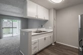 Located at 11902 Central Ave in Chino, CA, this 1-bedroom, 1-bathroom unit offers a well-organized, single-floor layout that makes efficient use of its compact footprint. The open-concept kitchen flows directly into the living area, creating a connected and functional common space. The kitchen features white cabinetry with brushed nickel hardware, a double-basin stainless steel sink, white countertops with a light blue accent wall, light wood-style flooring, and stainless steel appliances including a refrigerator and range. The living area is carpeted and bathed in natural light from a sliding glass door fitted with vertical blinds, which opens to an outdoor view. The bedroom is generously proportioned for the overall unit size, offering soft carpeting, a window with blinds for natural light, a textured ceiling, and built-in open shelving for convenient storage. The bathroom is clean and well-appointed, featuring a white vanity with a quartz-style countertop, a large mirror, and a shower-tub combo with a curved curtain rod and handheld showerhead, complemented by wood-style flooring. A hallway connects the main rooms, completing this thoughtfully laid-out home.