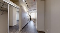 Located on the second floor at 10620 116 Street NW in Edmonton, this 2-bedroom, 2-bathroom unit combines contemporary design with industrial-inspired architectural details. The exposed concrete ceiling serves as a defining feature throughout the main living and kitchen areas, complemented by a black track lighting system that provides both functional illumination and a modern aesthetic. Dark hardwood-style flooring runs throughout, grounding the space with warmth and continuity.

The kitchen is well-appointed with floor-to-ceiling light wood-grain cabinetry offering generous storage, stainless steel appliances including a range, built-in microwave, and refrigerator, plus a light-toned countertop and undermount sink. A freestanding kitchen island adds additional workspace and defines the transition toward the living area. Large windows allow natural light to fill the space, enhancing the open feel.

The two bathrooms are finished with clean, contemporary fixtures and large-format white tile. One bathroom features a sliding glass-door walk-in shower, while the second includes a soaker tub with tiled surround. Both feature stone-effect countertops and mirrored medicine cabinets. An in-unit stacked washer and dryer is also present, adding everyday practicality to this efficiently designed urban residence.