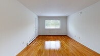 Located at 63 Stoneycrest Drive in Middletown, Connecticut, this one-bedroom, one-bathroom residence offers a practical and well-organized single-floor layout. Warm, polished hardwood floors flow throughout the living room, hallway, and bedroom, lending the space a clean and inviting character.

The combined kitchen and living area is anchored by a bright, functional kitchen featuring warm wood cabinetry, dark countertops, a white electric range, refrigerator, and dishwasher. A large window allows natural light to fill the space, creating an open and airy feel. Light-toned flooring in the kitchen complements the overall neutral palette of the home.

The living room is spacious and open, with gleaming hardwood floors, white walls, and a large window that invites additional natural light and outdoor views. Baseboard heating runs throughout, ensuring year-round comfort.

The bedroom is a well-sized private retreat, also featuring hardwood floors, a window with natural light, and a full-size closet with double doors — offering ample storage. A connecting hallway links the bedroom to the rest of the home.

The bathroom is finished with classic white square wall tiles, a mosaic tile floor, a white vanity with sink, toilet, and a window that provides natural light and ventilation. A mirror cabinet above the vanity adds both function and brightness to the room.