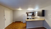 Located at 1015 Glendale Dr in Greensboro, NC, this single-floor unit offers a practical and functional layout designed for comfortable everyday living. The kitchen is a standout feature, equipped with dark espresso cabinetry that provides ample storage, a white appliance suite including a refrigerator, electric range, and over-the-range microwave, and a light-toned countertop that extends into a peninsula — ideal for casual dining or additional prep space. Wood-look flooring in the kitchen and entryway adds a durable, easy-to-maintain surface in high-traffic areas. The adjacent living area is generously sized, featuring neutral carpet, a textured ceiling, and a window that brings in natural light and outdoor views. A baseboard heating system is present throughout the unit. The bedroom is a calm, well-proportioned space with soft carpet, a window fitted with blinds for privacy, and a wall-mounted air conditioning unit for climate control. The bathroom includes a full-size tub and shower combination with a built-in grab bar, offering both practicality and safety. Throughout the unit, neutral wall tones and flush-mount lighting create a clean, move-in-ready atmosphere.