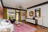 This single-floor residence showcases a cohesive design aesthetic anchored by rich, dark cabinetry and warm wood-look flooring that flows through the main living spaces. The kitchen is a standout area, featuring dark espresso cabinetry with ample storage, granite countertops, a central island, a mosaic tile backsplash, and a full suite of stainless steel appliances, including a range, over-the-range microwave, and refrigerator. A farmhouse-style sink adds a distinctive touch.

The living area is bright and welcoming, with bold crown molding in dark trim, a ceiling fan, built-in shelving, and an elegant arched entryway that connects spaces with architectural character. Rich wood-look flooring continues throughout, complementing the neutral walls.

The bedrooms are carpeted for comfort, each offering a calm retreat. Dark-trimmed doorways provide visual continuity with the rest of the unit.

The bathrooms are well-appointed, featuring extended granite vanity countertops, dark cabinetry with brushed nickel hardware, large mirrors with overhead lighting, wood-look flooring, and a separate soaking tub and glass-enclosed shower, creating a refined, spa-inspired atmosphere.