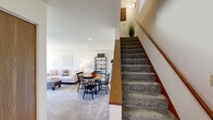 This two-story home offers a well-organized layout spread across two floors, providing comfortable living spaces throughout. The main level features an open-concept living and dining area, where soft carpet flooring and neutral walls create a bright, welcoming atmosphere. A sliding glass door in the living room fills the space with natural light and provides views of the surrounding greenery. The adjacent galley-style kitchen is outfitted with warm wood cabinetry, light countertops, black appliances including a refrigerator, range, microwave, and dishwasher, and durable hardwood-style flooring. A large window at the kitchen's dining nook further enhances the sense of openness. A full bathroom on the main level offers a single vanity with clean, simple finishes. A carpeted staircase with a warm wood handrail leads to the upper floor, where both bedrooms are located. The generously sized primary bedroom features vaulted ceilings, a closet, and a window overlooking the outdoors. The second bedroom is similarly comfortable with ample natural light. The upper-level bathroom is notably spacious, featuring dual vanities with wood cabinetry, a tub-shower combination, and hardwood-style flooring, making it a practical and well-appointed space. Throughout, the home maintains a consistent, clean aesthetic with neutral tones and functional design.