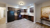 Located at 617 N Notre Dame Ave in South Bend, Indiana, this single-floor, 3-bedroom, 2-bathroom home offers a well-designed layout with a comfortable and functional living experience. The open-concept living room flows seamlessly into the kitchen, featuring rich dark wood cabinetry, light countertops, black appliances including a refrigerator, range, microwave, and dishwasher, and recessed lighting that brightens the space. Durable hardwood-style flooring runs throughout the main living areas, lending a clean, modern aesthetic. The living room is generously sized, bathed in natural light from multiple windows fitted with blinds. Each of the three bedrooms is carpeted for warmth and comfort, with windows providing natural light and neutral walls offering a versatile backdrop. The spacious primary bedroom provides ample room for a full suite of furniture. Both bathrooms are well-appointed, with one featuring a tub/shower combination. A dedicated in-unit laundry room with full-size washer and dryer hookups and overhead shelving adds everyday convenience. A hallway and closet round out the thoughtfully organized floor plan, making this home practical and move-in ready.