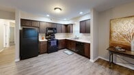 Located at 617 N Notre Dame Ave in South Bend, Indiana, this single-floor, 3-bedroom, 2-bathroom home offers a well-designed layout with a comfortable and functional living experience. The open-concept living room flows seamlessly into the kitchen, featuring rich dark wood cabinetry, light countertops, black appliances including a refrigerator, range, microwave, and dishwasher, and recessed lighting that brightens the space. Durable hardwood-style flooring runs throughout the main living areas, lending a clean, modern aesthetic. The living room is generously sized, bathed in natural light from multiple windows fitted with blinds. Each of the three bedrooms is carpeted for warmth and comfort, with windows providing natural light and neutral walls offering a versatile backdrop. The spacious primary bedroom provides ample room for a full suite of furniture. Both bathrooms are well-appointed, with one featuring a tub/shower combination. A dedicated in-unit laundry room with full-size washer and dryer hookups and overhead shelving adds everyday convenience. A hallway and closet round out the thoughtfully organized floor plan, making this home practical and move-in ready.