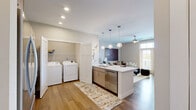 Located at 2329 Remington Way in Lexington, Kentucky, this well-appointed one-bedroom, one-bathroom residence offers a thoughtfully designed single-floor layout that maximizes comfort and functionality. The open-concept living and kitchen area serves as the heart of the home, featuring warm hardwood-style flooring, a ceiling fan, and French doors that flood the space with natural light while providing outdoor views. The kitchen is equipped with stainless steel appliances, light wood cabinetry, a subway tile backsplash, and a large quartz-topped island with seating — illuminated by a trio of globe pendant lights. A dedicated in-unit laundry closet with a full-size washer and dryer adds everyday convenience. The spacious bedroom offers plush carpet, a ceiling fan, and bright windows that invite natural light, providing a calm and restful retreat. A generously sized closet is also found within the bedroom area. The bathroom features wood-look flooring, a white vanity, and a full tub-and-shower combination finished with elegant marble-style tile surround. Neutral tones and clean lines throughout create a cohesive, modern aesthetic that is both welcoming and refined.