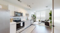 Located at 100 E Tyler St. in Tampa's vibrant Hyde Park neighborhood, this modern single-floor unit offers a thoughtfully designed open layout with contemporary finishes throughout. The kitchen is a standout feature, outfitted with sleek white cabinetry, a classic subway tile backsplash, light quartz countertops, and a full suite of stainless steel appliances including a range, microwave, dishwasher, and refrigerator. Track lighting overhead adds a polished, functional touch. The kitchen flows seamlessly into the living area, where floor-to-ceiling windows flood the space with abundant natural light and frame sweeping elevated views of the Tampa skyline and surrounding cityscape. The bedroom continues the bright, airy aesthetic with large windows offering the same impressive views, and includes ample space for a full sleeping and workspace setup. A walk-in closet with built-in shelving provides excellent storage. The bathroom features a wide vanity with a single undermount sink, light wood-toned cabinetry, a tiled walk-in shower, and clean tile flooring. Wood-style plank flooring runs throughout the main living areas, tying the space together with a warm, modern feel.