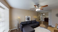 This single-story, one-bedroom, one-bathroom unit delivers a practical and comfortable layout across a well-utilized floor plan. The living room serves as the heart of the home, featuring warm-toned walls, rich hardwood-style flooring, and a ceiling fan with light fixture overhead. A large window fills the space with natural light and provides views of greenery outside, creating an inviting atmosphere. The open sightline from the living area toward the entry and kitchen enhances the sense of flow throughout.

The galley-style kitchen is efficiently designed, featuring white cabinetry on both sides, granite-style countertops, a double stainless steel sink, and white appliances including a range, dishwasher, and refrigerator. Light tile flooring and under-cabinet lighting contribute to a clean, functional workspace. A pendant light at the kitchen's opening connects it visually to the dining and entry area.

The bedroom is generously proportioned, with plush carpeting, a ceiling fan, a window with natural light, and a louvered closet door providing ample storage. The neutral tones promote a calm, restful environment.

The bathroom features a wide vanity with granite-style countertops, white cabinetry, a large mirror with a lighted fixture above, and tile flooring. A built-in linen closet adds additional storage convenience.