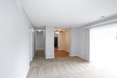 This single-floor residence offers a practical and straightforward layout across several rooms. The living area is generously proportioned, featuring neutral-toned wall-to-wall carpeting and a large sliding glass door fitted with vertical blinds that allows natural light to fill the space. A second carpeted room, likely a bedroom, mirrors this aesthetic with its own closet and ceiling fan with integrated lighting, along with a window that provides additional natural light.

The kitchen is functionally designed with warm wood-look vinyl flooring, white cabinetry extending to the ceiling for ample storage, and a full suite of black appliances including a gas range, dishwasher, and refrigerator. A built-in range hood and a stainless steel sink complete the workspace.

The bathroom features wood-look vinyl flooring consistent with the kitchen, a full tub-shower combination with white tile surround, a toilet, and a vanity with sink. A towel bar is conveniently positioned near the tub.

Throughout the residence, light gray walls, white trim, and textured ceilings create a clean, neutral palette. The 3D floor plan reveals a well-connected layout with clear sight lines between the living areas and kitchen, making the overall space feel cohesive and easy to navigate.