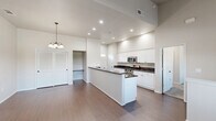 Located at 2627 Ashlan Ave in Clovis, CA, this two-story, 2-bedroom, 2-bathroom home offers a well-organized layout across two levels. The main living floor is expansive, hosting a combined living room, dining room, and kitchen in an open-concept arrangement. The living room impresses with soaring vaulted ceilings, a ceiling fan, rich hardwood-style flooring, and large windows that invite abundant natural light. The kitchen is well-appointed with crisp white cabinetry, dark granite countertops, stainless steel appliances including a gas range and built-in microwave, and a central island that doubles as a breakfast bar. A dedicated pantry and entrance area round out the main floor, along with a full bathroom featuring wood-style flooring, white cabinetry, and granite countertops. Upstairs, both bedrooms are carpeted and feature vaulted ceilings and windows with natural light. A second full bathroom includes a tub/shower combo with sliding glass doors. The home also features a covered balcony with black metal railings offering open neighborhood views, carpeted stairs with a sleek metal railing, multiple closets, a hallway, and an in-unit laundry room for added convenience.