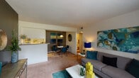 This single-floor residence offers a thoughtfully designed layout that balances comfort and functionality. The open-plan living and dining area forms the heart of the home, with soft carpet underfoot, neutral walls, and natural light filtering through a large window dressed with curtains and blinds. The living space flows seamlessly into a defined dining nook, separated by a half-wall pass-through from the kitchen, creating a connected yet distinct entertaining area.

The galley-style kitchen is efficiently organized, featuring white cabinetry, a coil-top range, dishwasher, refrigerator, and a stainless steel sink. A built-in pantry closet provides generous additional storage. Hardwood-style flooring adds warmth to this functional cooking space.

The two bedrooms are carpeted and comfortably sized, each offering windows that allow natural light to fill the room. One bedroom features a serene sage-toned accent wall, while the other is highlighted by a bold teal feature wall, giving each room its own distinct character.

Two full bathrooms each include a tiled soaking tub and shower combination, with hardwood-style flooring and a vanity with ample counter space. The overall layout is practical and well-proportioned, making efficient use of every area throughout this single-level home.
