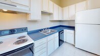 Located at 25 Dorrance St in the heart of downtown Providence, Rhode Island, this single-floor unit offers a thoughtfully laid-out interior with a variety of functional spaces. The centerpiece of the unit is a generously sized open main area that spans a considerable footprint, finished with gleaming polished tile flooring that reflects natural light throughout the day. Multiple large windows with dark wood frames line the perimeter, framing views of the surrounding urban streetscape and flooding the interior with abundant daylight. Black track lighting systems mounted to the white ceilings provide adjustable, directed illumination suited to a variety of uses.

The kitchen features white cabinetry extending to the upper walls, bold blue laminate countertops, a stainless steel sink, an electric range, a dishwasher, and a full-size refrigerator, offering practical functionality in a compact layout.

The full bathroom is finished in a clean, neutral palette with light tile flooring, a white vanity with cabinet storage, a wall-mounted mirror with overhead lighting, and a full bathtub with shower.

A dedicated walk-in closet provides substantial storage capacity, outfitted with multi-tiered wire shelving and a hanging rod along the walls. The overall ambiance of the unit is bright, open, and versatile.