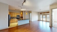This single-floor residence offers a thoughtfully designed open-concept layout that seamlessly connects the kitchen, dining, and living areas. The kitchen is a standout feature, outfitted with light maple cabinetry extending to the ceiling, stainless steel appliances including a refrigerator, electric range, and microwave, complemented by rich granite countertops and a tile backsplash. A central island with a built-in sink and pendant lighting above adds both functionality and style. Track lighting throughout the kitchen and living areas provides ample illumination, while warm hardwood flooring flows across the main living spaces.

The living area is bright and airy, benefiting from natural light that pours in through a set of large French doors fitted with wood-toned blinds. The bedrooms are carpeted for comfort, each equipped with a ceiling fan and windows that invite natural light. The primary bathroom features a dual-sink vanity with granite countertops, tile flooring, and a separate water closet with a frosted-glass door. A secondary bathroom offers a tiled tub-and-shower combination, a single-sink vanity with granite countertops, and tile flooring. The overall palette of neutral tones and quality materials creates a clean, cohesive, and welcoming atmosphere throughout.