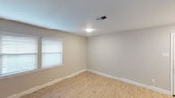 This single-floor space offers a well-organized layout with a consistent neutral color palette of soft grays and beiges throughout. The open living area features light wood-tone vinyl plank flooring, crisp white baseboards, and a flush-mounted ceiling light, creating a bright and clean aesthetic. A paneled entry door and a dedicated HVAC vent contribute to the room's functional design.

The kitchen is efficiently arranged in a U-shaped layout, equipped with white shaker-style cabinetry, granite-look countertops, a stainless steel double-basin sink, a black electric range, a built-in microwave, and a dishwasher. A window above the sink allows natural light to brighten the workspace.

The bedrooms feature plush neutral carpeting, ceiling light fixtures, and windows fitted with horizontal blinds. One bedroom includes an adjoining bathroom, while another offers a walk-in closet with built-in shelving. A separate room with vinyl plank flooring and a textured ceiling also provides additional flexible living space.

The bathroom is finished with white subway tile surrounding a soaking tub and shower combination, complemented by a granite-top vanity and brushed nickel fixtures, completing the space's cohesive and updated interior.