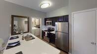 Located at 12235 Stone Arbor Way in Charlotte, NC, this single-floor residence offers a well-designed layout with thoughtfully appointed spaces throughout. The kitchen is equipped with stainless steel appliances, including a refrigerator, range, and built-in microwave, complemented by dark cabinetry, white countertops, and a double-basin sink. A convenient in-unit laundry area is accessible directly from the kitchen. The living room features wood-style flooring, neutral gray walls, a textured ceiling, and a bright window with access to natural light, creating a welcoming gathering space. Multiple bedrooms are carpeted and share a soft, neutral color palette, each with windows dressed in layered blinds and curtains that allow for ample natural light. The primary bedroom offers a serene retreat with views of surrounding greenery. The bathrooms are finished with dark vanity cabinetry, white countertops, wood-style flooring, and framed mirrors with vanity lighting. One bathroom includes a soaking tub with a curtained surround, while another features a spacious vanity area with additional storage. Throughout the residence, a consistent modern aesthetic is maintained with neutral tones, tasteful finishes, and functional design.