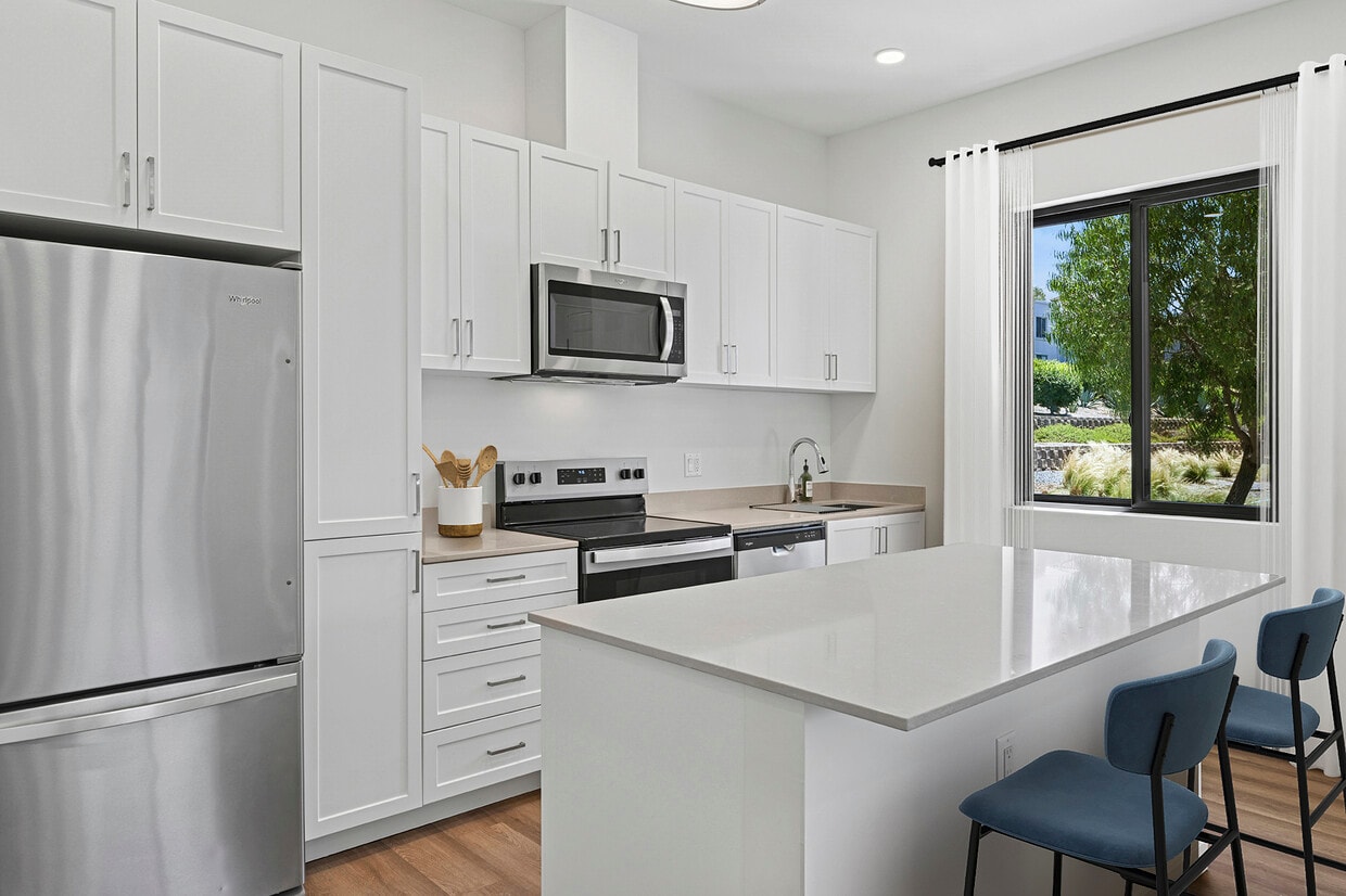 Freestanding Home kitchen with stainless steel appliances, white cabinetry, beige quartz countertops, and hard-surface flooring - eaves San Marcos