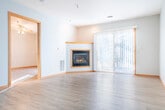 Located at 135 Marcou Rd in Onalaska, Wisconsin, this one-bedroom, one-bathroom unit offers a well-organized, single-floor layout with a comfortable and functional design throughout. The open-concept living and kitchen area forms the heart of the space, where light wood-tone flooring and neutral walls create a clean, welcoming ambiance. The living room is highlighted by a corner gas fireplace framed in warm wood trim and a sliding glass door that opens to a private balcony, filling the room with natural light and outdoor views of surrounding trees and greenery. A ceiling fan adds comfort to this central gathering space. The kitchen is efficiently designed with warm oak cabinetry, light countertops, a double-basin sink, a peninsula breakfast bar, and white appliances including a dishwasher and range. Tile flooring extends through the kitchen and into the bathroom and laundry areas. The bedroom features light wood flooring, warm wood-trimmed windows with pleasant outdoor views, and convenient closet access. The full bathroom includes a tub-shower combination, a single-sink oak vanity with mirror and overhead lighting, and tile flooring. A dedicated in-unit laundry room with full-size washer and dryer hookups adds everyday convenience. A separate closet provides additional storage.