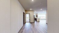 Located at 700 S Main St in Oshkosh, Wisconsin, this well-appointed 2-bedroom, 2-bathroom residence offers a thoughtfully designed layout across a single floor. The open-concept kitchen and living area serves as the heart of the home, showcasing rich dark wood cabinetry, granite countertops, stainless steel appliances including a full-size refrigerator, electric range, and microwave, as well as a central island with pendant lighting overhead. Durable hardwood-style flooring flows throughout the main living areas, complementing the warm, neutral color palette. The spacious living room is bathed in natural light from large windows with views of the surrounding neighborhood. The primary bedroom is generously sized, featuring plush carpeting, a ceiling fan, and direct access to a private balcony. The second bedroom also offers balcony access and ample natural light through large windows. Each bedroom is served by its own closet with wire shelving systems for organized storage. The primary bathroom features a granite-topped vanity, a walk-in shower, and hardwood-style flooring, while the second bathroom includes a full soaking tub and shower combination. Neutral tones and clean finishes throughout create a bright, move-in-ready atmosphere.