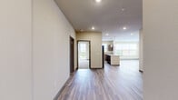 Located at 700 S Main St in Oshkosh, Wisconsin, this well-appointed 2-bedroom, 2-bathroom residence offers a thoughtfully designed layout across a single floor. The open-concept kitchen and living area serves as the heart of the home, showcasing rich dark wood cabinetry, granite countertops, stainless steel appliances including a full-size refrigerator, electric range, and microwave, as well as a central island with pendant lighting overhead. Durable hardwood-style flooring flows throughout the main living areas, complementing the warm, neutral color palette. The spacious living room is bathed in natural light from large windows with views of the surrounding neighborhood. The primary bedroom is generously sized, featuring plush carpeting, a ceiling fan, and direct access to a private balcony. The second bedroom also offers balcony access and ample natural light through large windows. Each bedroom is served by its own closet with wire shelving systems for organized storage. The primary bathroom features a granite-topped vanity, a walk-in shower, and hardwood-style flooring, while the second bathroom includes a full soaking tub and shower combination. Neutral tones and clean finishes throughout create a bright, move-in-ready atmosphere.