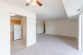 This single-floor residential unit offers a practical and comfortable layout designed for everyday living. The expansive living area is finished with neutral-toned carpet and features a ceiling fan, creating a bright and airy atmosphere. A dedicated entry area provides a smooth transition into the main living space.

The kitchen is efficiently laid out with warm wood cabinetry extending to the upper walls, offering ample storage. Granite-look laminate countertops run along two walls, accompanied by a double sink, a gas range, a dishwasher, and a full-size refrigerator. Tile flooring in the kitchen adds a practical contrast to the carpeted living areas.

The bedrooms are generously sized, each carpeted and finished in soft neutral tones. Multiple bedrooms include closets with bifold doors, providing convenient storage. Large windows in the corner bedroom allow natural light to flow in from two directions, offering pleasant outdoor views.

The bathroom is clean and functional, featuring a full tub-and-shower combination with tiled surround, a toilet, a single-sink vanity with wood cabinetry, and tile flooring. The overall layout, as visible in the dollhouse view, is well-organized and maximizes usable square footage throughout.