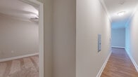 Located at 404 W Smith St in Greensboro, NC, this well-appointed one-bedroom, one-bathroom residence offers a thoughtfully designed single-floor layout. The open living and kitchen area features warm hardwood flooring, crown molding, and a large window with plantation-style shutters that flood the space with natural light. The kitchen is equipped with stainless steel appliances, including a range, microwave, and dishwasher, complemented by rich wood cabinetry, granite-look countertops, and a classic white subway tile backsplash. A hallway connects the main living area to the private bedroom and bathroom. The bedroom is carpeted for comfort, features a ceiling fan with light fixture, and includes a double-door closet, providing practical storage. An adjacent doorway leads conveniently to the bathroom. The full bathroom is finished with tile flooring, a tub-shower combination, a wood vanity with granite countertop, a large mirror, and built-in shelving for added storage. Neutral tones throughout the home create a clean, cohesive aesthetic. The hallway is finished with hardwood flooring and crisp white trim, maintaining a polished look from entry to bedroom.