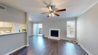 This single-floor, one-bedroom residence offers a thoughtfully designed layout that maximizes its compact footprint. The open-concept living and dining area serves as the heart of the space, featuring rich dark hardwood-style flooring, crown molding, and a ceiling fan with integrated lighting. A white-surround fireplace anchors the main living area, while a sliding glass door floods the room with natural light and provides access to an outdoor balcony. A secondary window further brightens the space with views of the surrounding exterior.

The galley-style kitchen is efficiently designed with white cabinetry, white countertops, a stainless steel sink, and stainless steel appliances including a range and refrigerator. The layout maximizes storage and counter space within a streamlined corridor arrangement.

The bedroom offers a comfortable and quiet retreat, finished with plush carpet, a ceiling fan, and a window that brings in natural light. A dedicated walk-in closet off the bedroom provides ample storage with wire shelving and hanging rods on multiple walls.

The bathroom is clean and functional, featuring white vanity cabinetry, a single-sink countertop, a lighted mirror, and a shower-tub combination. The space is completed by a dedicated entrance area that provides a smooth transition into the home.