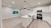This two-story residence offers a thoughtfully designed layout across two levels, with the majority of the living space situated on the upper floor. The open-concept kitchen serves as a central highlight, featuring a large island with a granite countertop, an undermount sink, white shaker cabinetry, stainless steel appliances including a range, microwave, and refrigerator, and striking black pendant lights overhead. Light wood-look flooring runs throughout the main living areas, complementing the neutral, warm-toned walls and clean white trim.

The three bedrooms are carpeted for comfort and each includes a ceiling fan and window blinds that allow for natural light. The spacious primary bedroom offers a generous footprint, while the additional bedrooms are well-sized and versatile. Each bedroom benefits from access to ample closet space, with three closets distributed throughout the home.

Both bathrooms are finished with granite-topped white vanities, light wood-look flooring, and tub-shower combinations, maintaining a consistent, polished aesthetic. A dedicated laundry room provides in-unit washer and dryer hookups along with overhead wire shelving for added storage. A hallway and staircase connect the levels, completing this functional and move-in ready home.