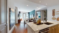 This thoughtfully designed single-floor residence offers a seamless open-concept layout connecting the kitchen, dining, and living areas. The kitchen serves as a central hub, featuring stainless steel appliances, wood-grain cabinetry, a subway tile backsplash, and an expansive granite-topped island with an undermount sink and bar seating—ideal for both cooking and entertaining. Warm hardwood flooring flows throughout the main living areas, complementing the clean white walls and recessed lighting overhead.

The living room is anchored by a striking teal accent wall, French doors that invite natural light, and direct outdoor access. The space comfortably accommodates a full seating arrangement and media setup.

Two well-proportioned bedrooms each feature tray ceilings, large windows, plush carpeting, and ceiling fans. Both offer a calm, serene atmosphere with ample natural light.

Each bathroom is distinctly finished—one showcases bold geometric mosaic tile flooring with wood-tone vanity and a tub/shower combination, while the other features elegant speckled tile, a double vanity, and refined neutral tones. Both bathrooms provide direct access to generously sized walk-in closets with built-in shelving, offering excellent storage throughout the residence.