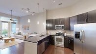 Located in Charlotte's vibrant Elizabeth neighborhood, this one-bedroom, one-bathroom residence offers a thoughtfully designed single-level floor plan that maximizes every square foot. The open-concept kitchen and living area forms the heart of the home, where rich dark hardwood floors run throughout. The kitchen is outfitted with dark espresso cabinetry, granite countertops, a tile backsplash, stainless steel appliances including a French door refrigerator, gas range, and microwave, plus a peninsula with pendant lighting that doubles as a dining space. The living room opens directly onto a private balcony through full-height French doors, filling the space with natural light and outdoor views. The spacious bedroom features elevated ceilings with a ceiling fan, dark hardwood floors, and generous natural light from a large window. The full bathroom is finished with neutral large-format tile, a soaking tub with a tiled surround, a dark vanity with an undermount sink, and open shelving. A dedicated laundry room with a full-size washer and dryer adds everyday convenience. A closet and hallway complete this well-appointed, efficiently laid-out residence.
