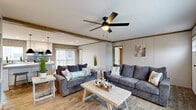 This single-story, 3-bedroom, 2-bathroom home delivers a thoughtfully designed floor plan that balances comfort and functionality. The open-concept living room serves as the heart of the home, featuring warm wood-look flooring, decorative ceiling beams, and a ceiling fan with light. Large windows allow natural light to fill the space, while built-in shelving adds both character and practicality.

The kitchen is a standout feature, showcasing white shaker-style cabinetry, stainless steel appliances, a central island with seating, and stylish black pendant lighting overhead. Light hardwood flooring carries through seamlessly from the living area into the kitchen, reinforcing the open feel.

The primary bedroom is a well-proportioned retreat, complete with plush carpeting, dual windows offering natural light, and a ceiling fan. The spacious walk-in closet includes wire shelving systems for organized storage. The secondary bedrooms are carpeted and bright, each featuring a window with a view to the outside.

Both bathrooms are finished with clean white vanities, wood-framed mirrors, and wood-look tile flooring. One bathroom includes a full tub-shower combination with modern matte black fixtures. The home also features a dedicated entrance and an overall neutral color palette that creates a bright, welcoming atmosphere throughout.