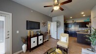 Located at City Base Landing in San Antonio, Texas, this single-floor residence offers a thoughtfully designed layout that balances comfort and modern style. The open-concept living and dining area is anchored by light wood-style flooring, neutral gray walls, and a ceiling fan overhead. Large windows allow generous natural light to fill the space, with a glass-top dining table positioned near a sliding door that provides outdoor access. The kitchen features dark cabinetry, granite-style countertops, a mosaic tile backsplash, and black appliances, including a refrigerator, range, and dishwasher. A peninsula counter adds additional workspace and visual separation from the living area. The bedroom is carpeted for warmth and comfort, with multiple windows, a ceiling fan, and direct access to a spacious walk-in closet with built-in shelving. The bathroom is finished with dark vanity cabinetry, granite-style countertops, wood-style flooring, and a shower-tub combination. Throughout the residence, consistent finishes and a cohesive neutral color palette create a polished, move-in-ready atmosphere suited for everyday living.