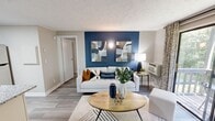 Located at 1505 Greenbrier Ridge Way in Knoxville, TN, this thoughtfully designed one-bedroom, one-bathroom residence offers a cohesive and modern aesthetic throughout its efficiently arranged single floor. The living room serves as the heart of the home, anchored by a bold navy blue accent wall adorned with contemporary artwork. Wood-style flooring runs throughout, complementing the neutral tones of the walls and textured ceiling. A sliding glass door floods the space with natural light and opens to a private balcony overlooking lush greenery, creating a seamless indoor-outdoor connection. The kitchen is well-appointed with crisp white shaker cabinets, granite countertops, stainless steel appliances including a refrigerator and dishwasher, and a skylight that adds an extra touch of brightness. The bedroom continues the bold design language with its own navy accent wall, a ceiling fan with light fixture, and a window that frames views of the surrounding foliage, contributing to a calm, nature-connected atmosphere. The bathroom features white cabinetry, a granite vanity, a framed mirror, and a shower-tub combination. A dedicated closet provides practical storage. This residence offers a refined, move-in-ready living experience with stylish modern touches throughout.