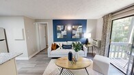 Located at 1505 Greenbrier Ridge Way in Knoxville, TN, this thoughtfully designed one-bedroom, one-bathroom residence offers a cohesive and modern aesthetic throughout its efficiently arranged single floor. The living room serves as the heart of the home, anchored by a bold navy blue accent wall adorned with contemporary artwork. Wood-style flooring runs throughout, complementing the neutral tones of the walls and textured ceiling. A sliding glass door floods the space with natural light and opens to a private balcony overlooking lush greenery, creating a seamless indoor-outdoor connection. The kitchen is well-appointed with crisp white shaker cabinets, granite countertops, stainless steel appliances including a refrigerator and dishwasher, and a skylight that adds an extra touch of brightness. The bedroom continues the bold design language with its own navy accent wall, a ceiling fan with light fixture, and a window that frames views of the surrounding foliage, contributing to a calm, nature-connected atmosphere. The bathroom features white cabinetry, a granite vanity, a framed mirror, and a shower-tub combination. A dedicated closet provides practical storage. This residence offers a refined, move-in-ready living experience with stylish modern touches throughout.
