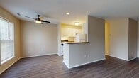 Located at 1709 Cresthill Ave in Royal Oak, Michigan, this single-floor unit offers a practical and well-appointed layout designed for comfortable everyday living. The open-concept living area is finished with dark hardwood-style flooring that extends throughout the main living spaces, complemented by neutral warm-toned walls and a ceiling fan overhead. A sliding glass door in the living room allows natural light to fill the space and provides outdoor access.

The kitchen is positioned adjacent to the living area and features a peninsula with a dark granite-style countertop that serves as a natural divider between the two spaces. White cabinetry, a stainless steel sink, matching dark countertops, and white appliances—including a refrigerator and range—complete the kitchen's clean and functional design. Windows above the kitchen provide additional natural light.

The bedrooms are carpeted and generously sized, offering neutral tones and ample wall space. One bedroom includes a window with outdoor views, contributing to a bright atmosphere.

Two bathrooms serve the unit, each finished with wood-style flooring and white vanities. One bathroom features a tub-shower combination with classic checkered tile accents and a large mirror, while the second offers a standalone glass-enclosed shower with matching tile detailing.